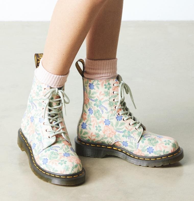 Person trägt floral gemusterte Stiefel mit rosa Socken.