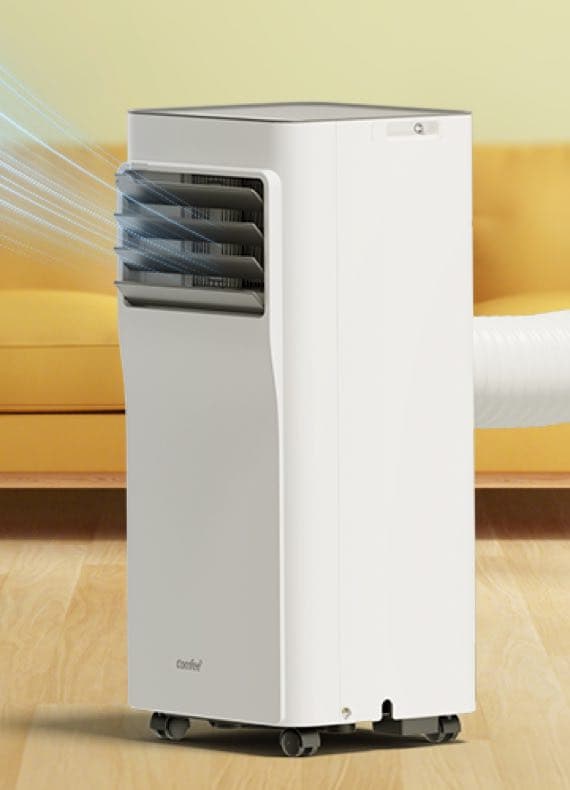 Mobiles Klimagerät mit Luftauslass und Abluftschlauch steht auf Rollen vor einem Sofa im Wohnzimmer