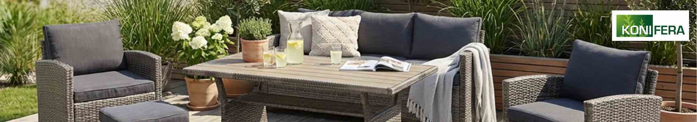 Gartenlounge mit Sofa, zwei Sesseln und Tisch mit Limonade, umgeben von Pflanzen und Holzsichtschutz im Hintergrund
