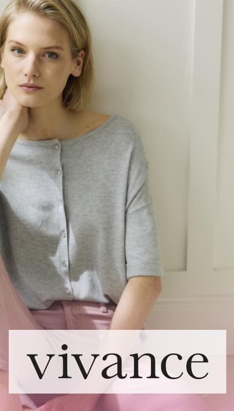 vivance – Person in grauem Oberteil und rosa Hose sitzt entspannt vor heller Wand