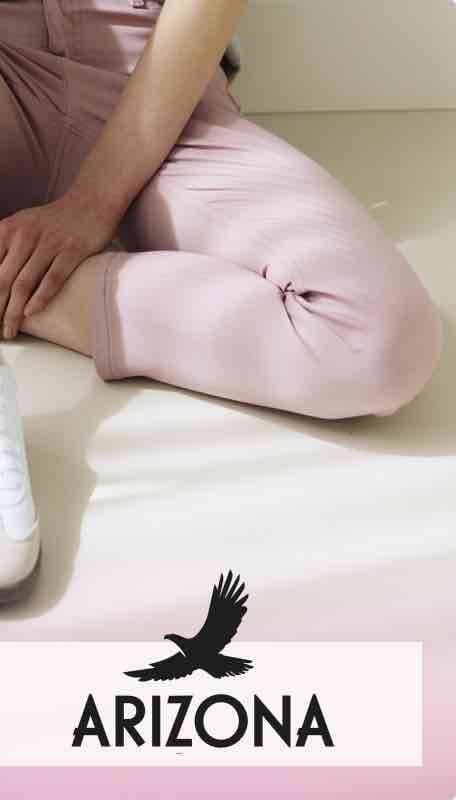 ARIZONA – Person in rosafarbener Hose sitzt auf dem Boden, Hände locker auf dem Bein abgelegt