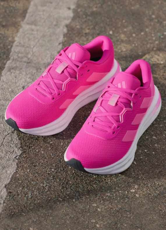 Paar pinke Laufschuhe mit Schnürung steht nebeneinander auf Asphaltboden