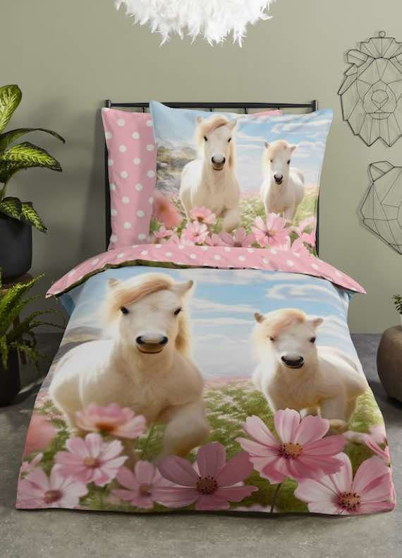 Bettwäsche mit zwei weißen Ponys auf Blumenwiese vor blauem Himmel, rosa Rand mit weißen Punkten