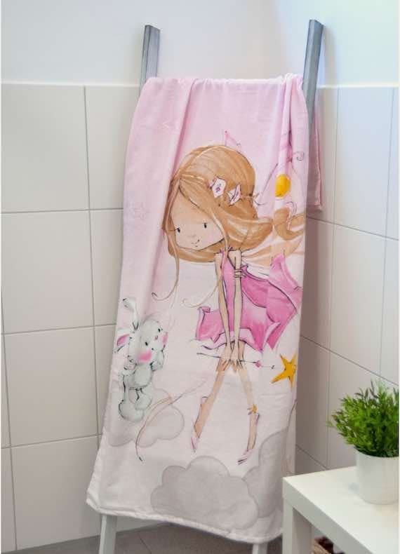 Rosa Kinderhandtuch mit Zeichnung eines Mädchens in Kleid und Hase auf Wolken, hängend im weißen Bad
