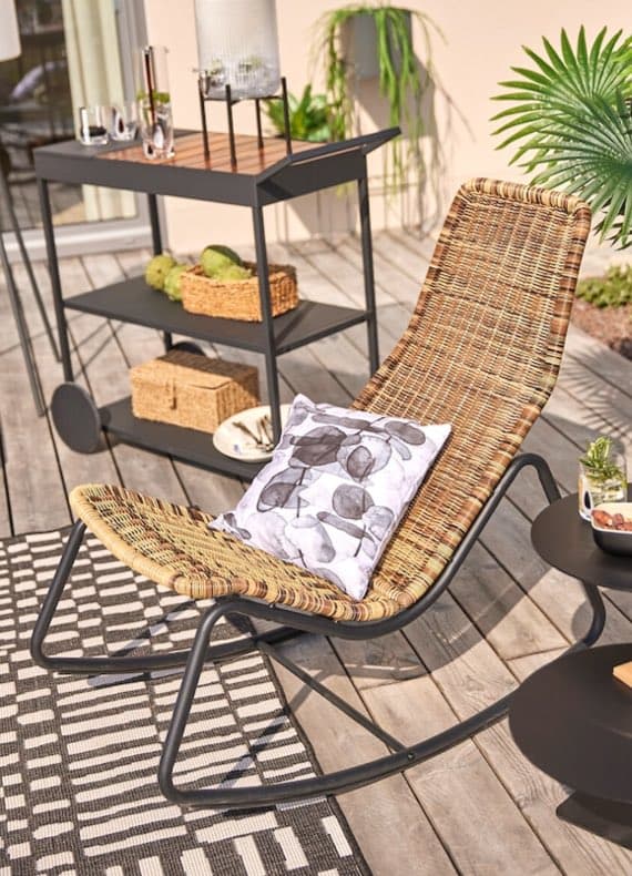 Liegestuhl mit gemustertem Kissen auf Holzterrasse, daneben Beistelltisch und Servierwagen mit Gläsern und Körben