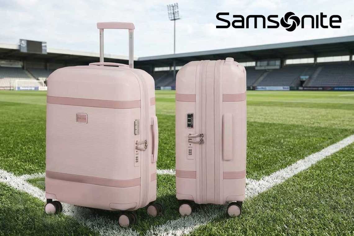 Samsonite – zwei rosafarbene Rollkoffer stehen nebeneinander auf dem Rasen eines Fußballstadions