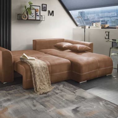 Großes braunes Schlafsofa im Dachzimmer, ausgezogen mit Kissen, Decke und Buch, davor Teppich und Blick über die Stadt