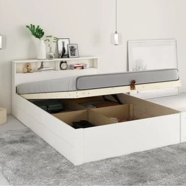 Weißes Bett mit hochgeklappter Matratze zeigt geräumigen Stauraum, Kopfteil mit Regalfächern und Deko im Schlafzimmer