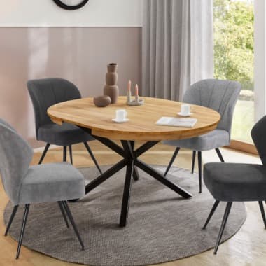 Runder Esstisch mit schwarzem Kreuzgestell, umgeben von vier grauen Stühlen auf rundem Teppich in hellem Esszimmer