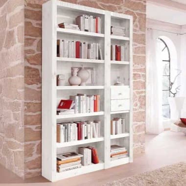 Weißes Regal mit vielen Büchern und Deko, steht vor Steinwand in hellem Wohnzimmer mit großem Bogenfenster