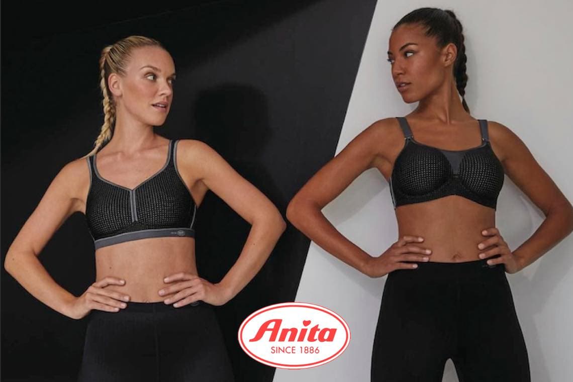 Anita since 1886 – zwei Frauen in schwarzen Sport-BHs stehen mit Händen in der Hüfte vor schwarz-weißer Wand