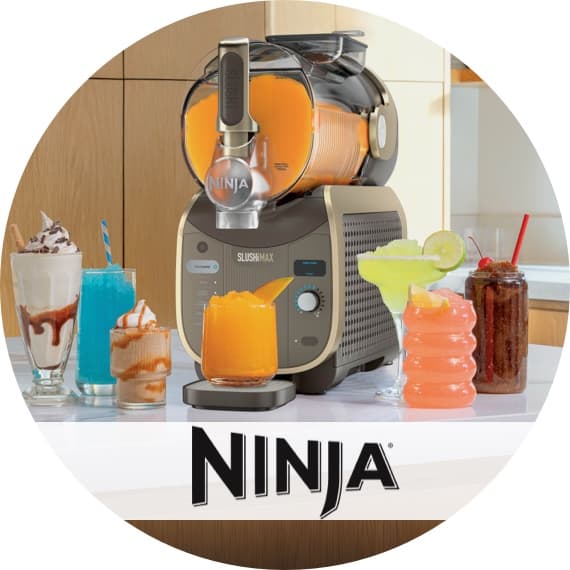 Ninja SlushMax Maschine zapft orange Slush in Glas, umgeben von bunten Slush-Getränken auf einer Küchenarbeitsplatte