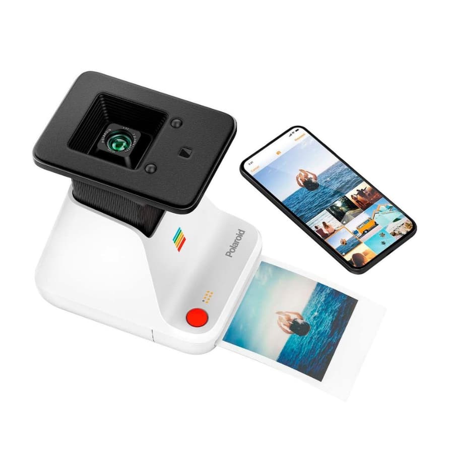 Polaroid-Drucker mit Smartphone daneben, das Fotos zeigt, vorne wird ein Sofortbild mit Meer und springender Person ausgegeben