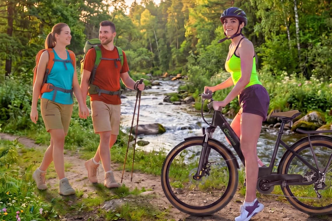Zwei Wandernde mit Rucksäcken treffen auf Frau mit Fahrrad an Bachlauf im grünen Waldweg