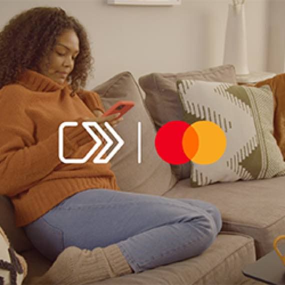 Mastercard Logo über Szene mit Person auf Sofa, die mit Smartphone in der Hand entspannt zurückgelehnt sitzt