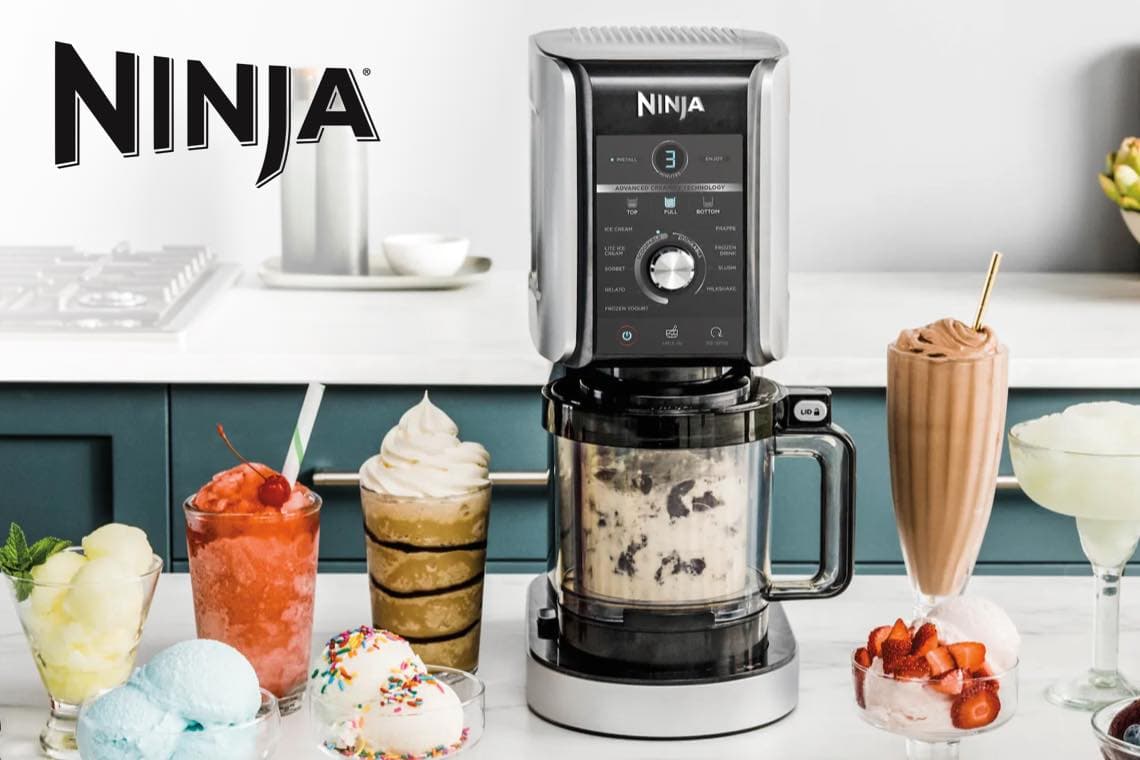 Ninja Küchenmaschine auf Arbeitsplatte, umgeben von Eisbechern, Milchshakes und Sorbets in verschiedenen Farben
