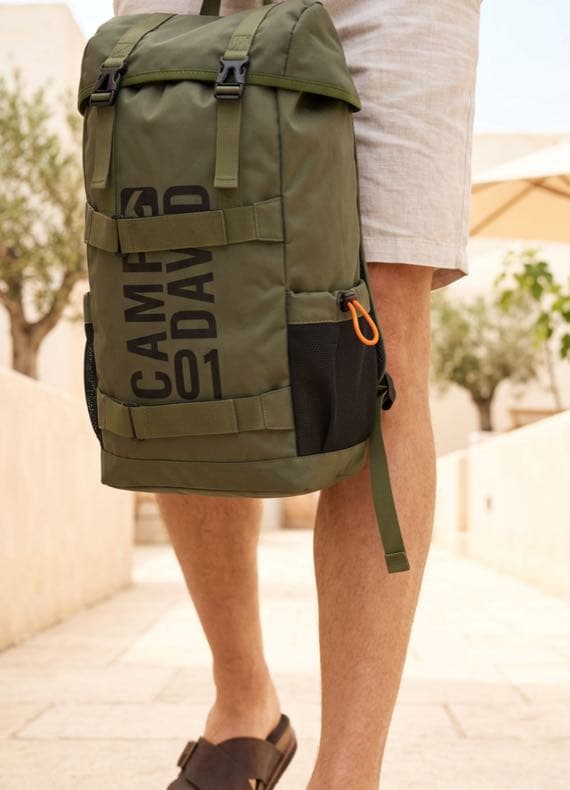 CAMP DAVID Rucksack in Oliv, von Mann in Shorts seitlich getragen, Fokus auf Taschen und Tragegurten