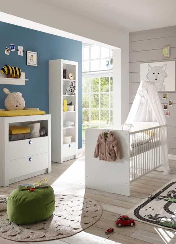 Helles Babyzimmer mit weißem Gitterbett, Wickelkommode, Regal, Spielteppich und Spielzeug vor großer Fensterfront