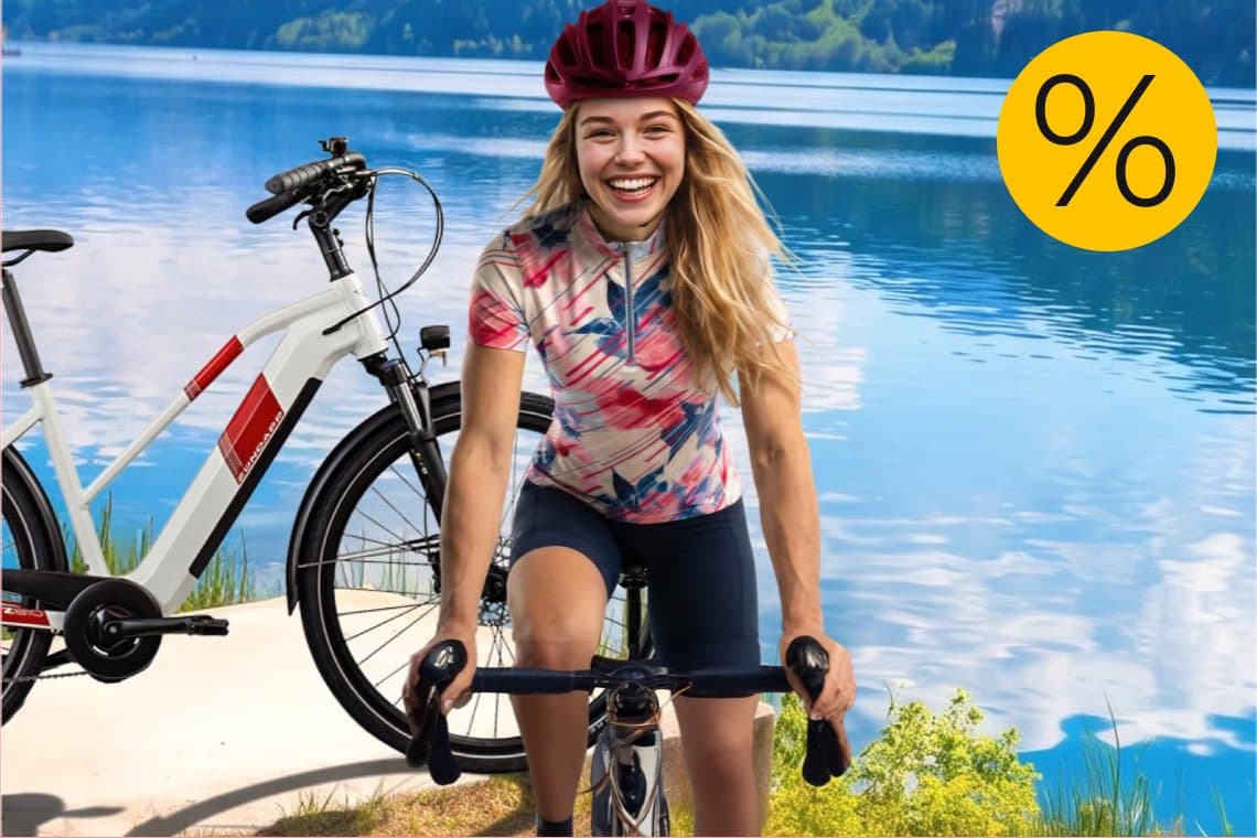 Prozentzeichen-Angebot – Frau mit Fahrradhelm fährt Rad am See, daneben steht ein weiteres Fahrrad am Ufer