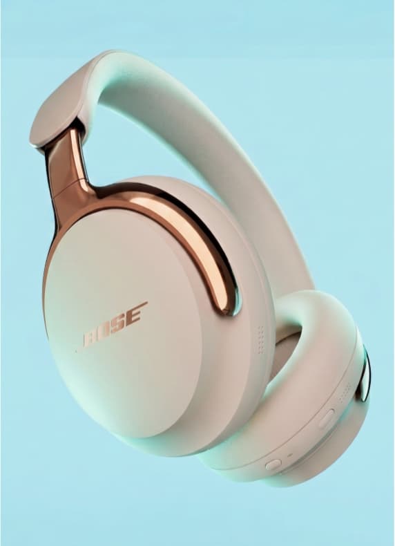 BOSE Over-Ear-Kopfhörer in hellem Ton mit kupferfarbenen Bügeln, seitlich vor blauem Hintergrund schwebend