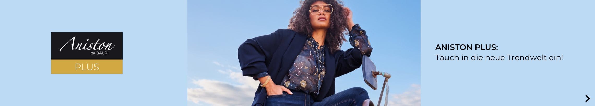 ANISTON PLUS – Frau mit Locken und Brille posiert selbstbewusst in Bluse und Blazer vor blauem Himmel