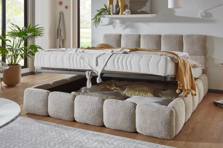 Bett mit hochgeklappter Matratze zeigt Stauraum darunter, dekoriert mit Kissen und Decken in modernem Schlafzimmer