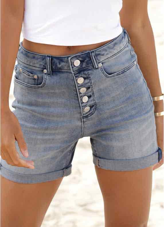 Frau in kurzer Jeans steht draußen und trägt ein weißes T-Shirt
