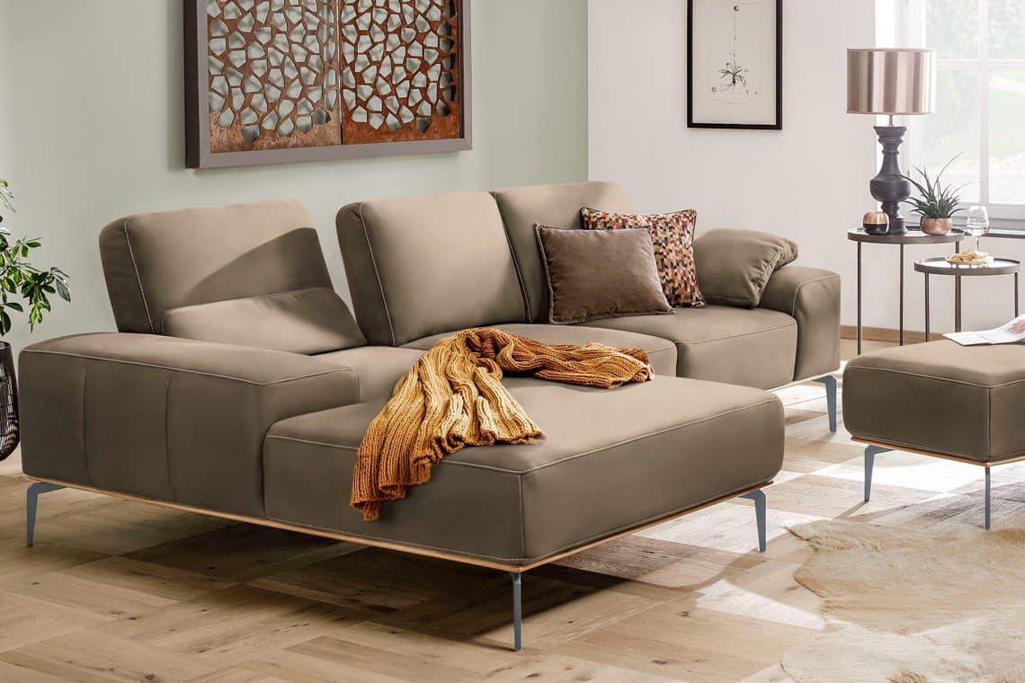 Ecksofa mit großer Liegefläche, gelber Decke und Kissen in modernem Wohnzimmer mit Beistelltischen und Lampe