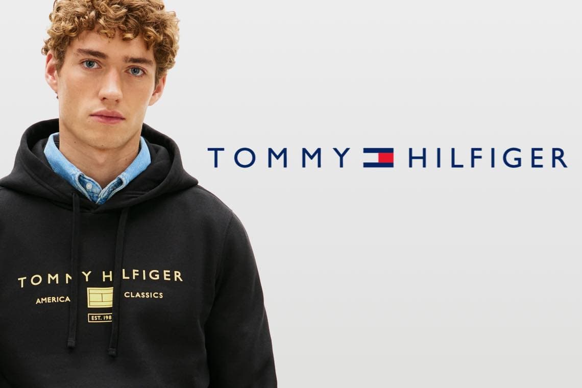 TOMMY HILFIGER Logo – junger Mann im schwarzen Hoodie mit Markenaufdruck schaut frontal in die Kamera