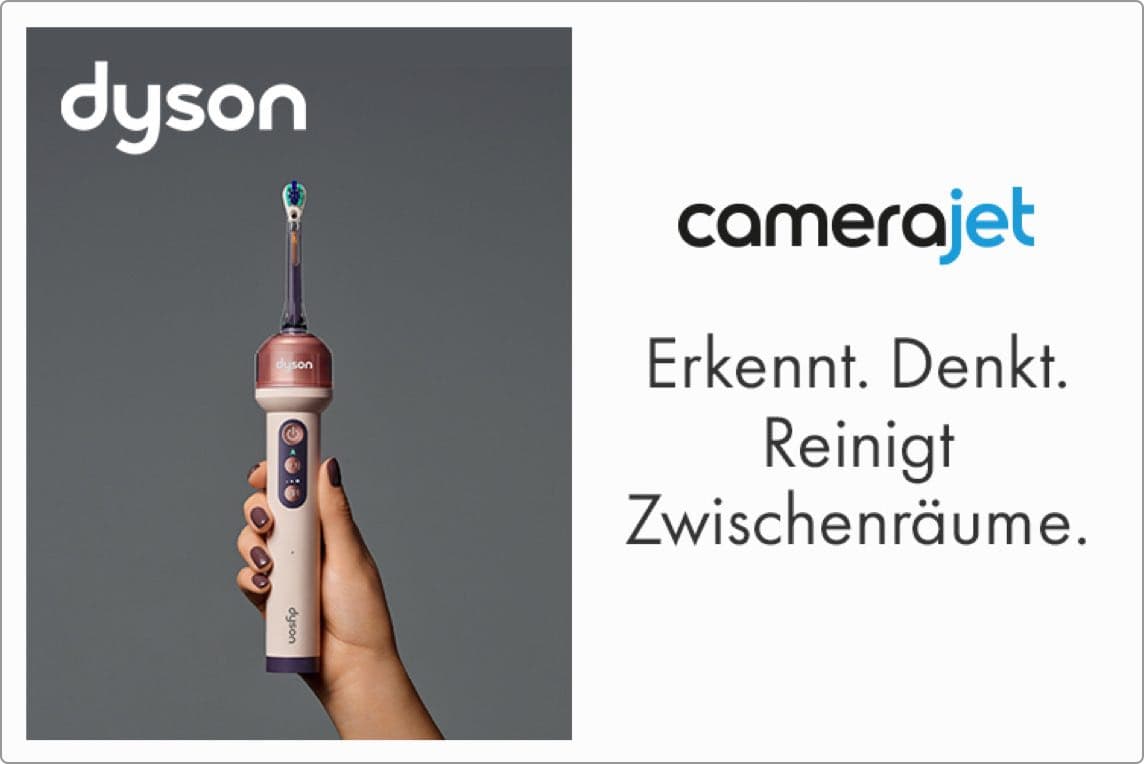 Erkennt. Denkt. Reinigt Zwischenräume – Hand hält elektrische Dyson-Zahnbürste vor grauem Hintergrund