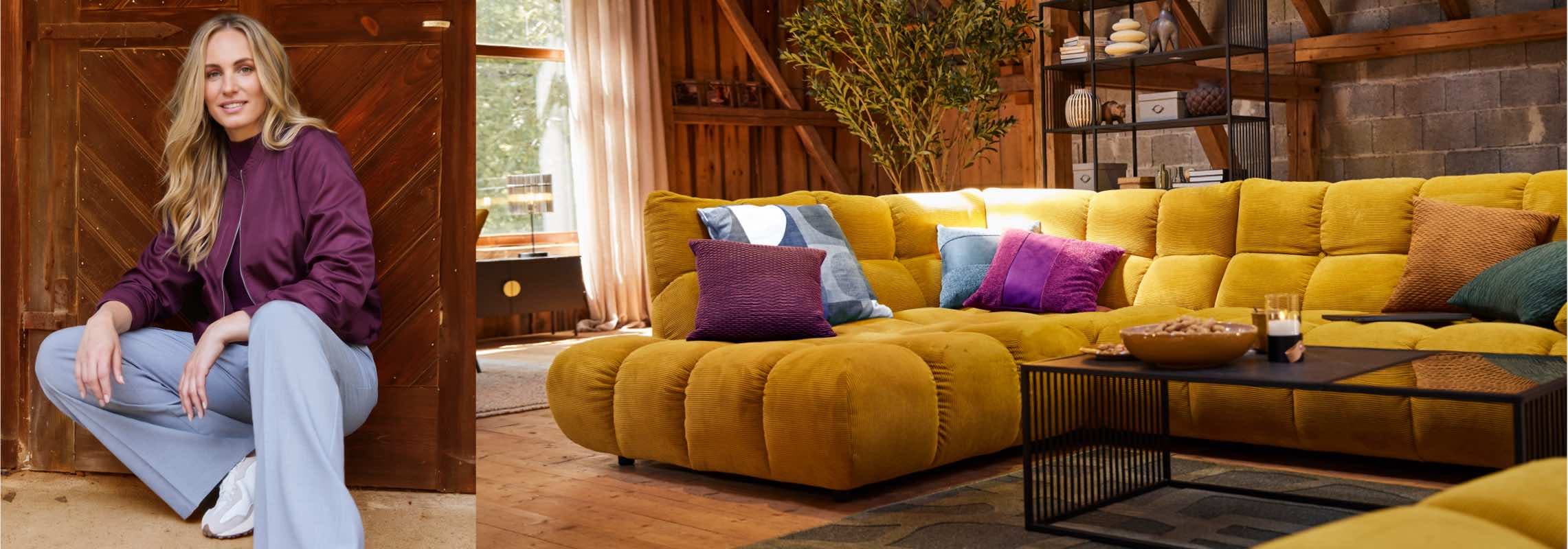 Frau sitzt vor Holztür, daneben großes gelbes Sofa mit bunten Kissen in gemütlichem Wohnzimmer