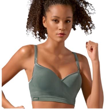 Frau in grünem BH mit geballter Faust und lockigem Haar