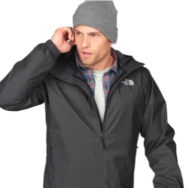 Person in grauer Jacke und grauer Mütze hebt die Hand ans Ohr