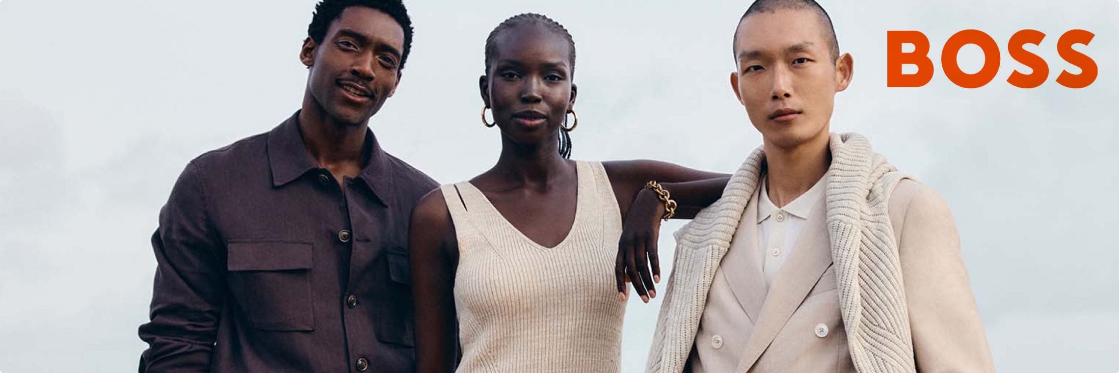 BOSS – Drei Personen in modischer Kleidung mit unkenntlichen Gesichtern posieren zusammen vor einem hellen Hintergrund.