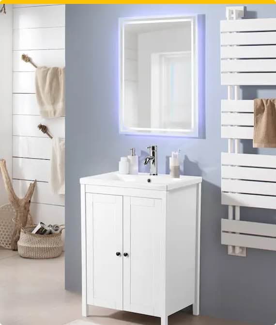 Badezimmer mit weißem Waschbeckenunterschrank, beleuchtetem Spiegel und Handtüchern auf weißem Handtuchhalter