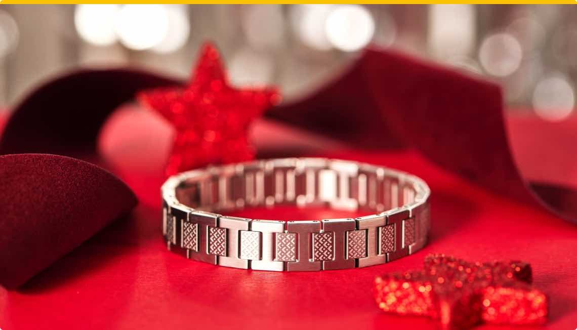 Silbernes Armband auf rotem Tisch, umgeben von roten Sternen und rotem Stoffband