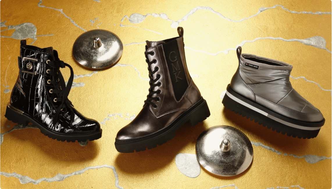 Drei verschiedene Stiefel auf goldenem Hintergrund – schwarz glänzend, braun mit GMK-Logo und silberne Winterstiefel
