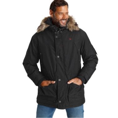 Mann trägt schwarze Winterjacke mit Pelzkragen und Knopfverschluss, Hände in den Taschen, blaue Jeans