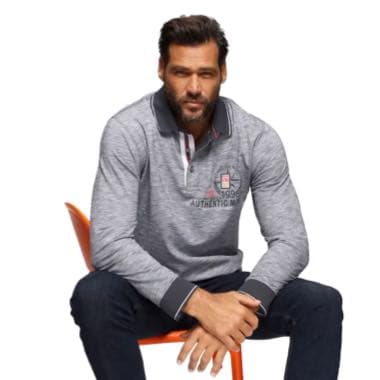 Mann in grauem Langarmshirt mit Aufdruck "Authentic" sitzt auf einem orangefarbenen Stuhl