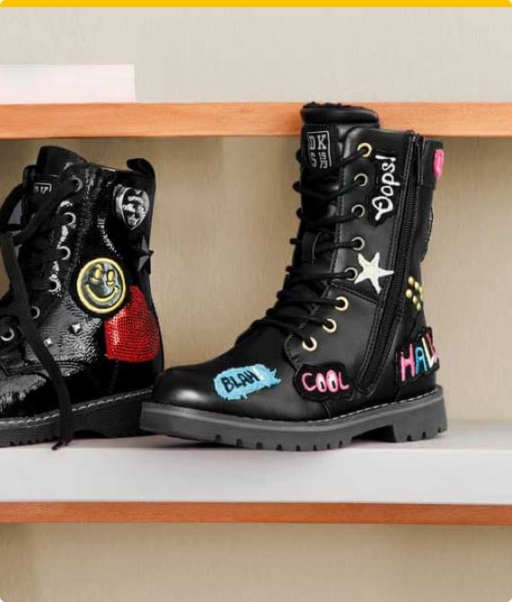 Zwei schwarze Stiefel mit bunten Aufnähern und Stickereien wie Smileys, Sternen und Schriftzügen wie "COOL" und "HALLO"