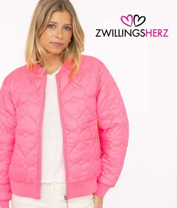 Frau in pinker Steppjacke vor weißem Hintergrund, ZWILLINGS HERZ Logo oben rechts